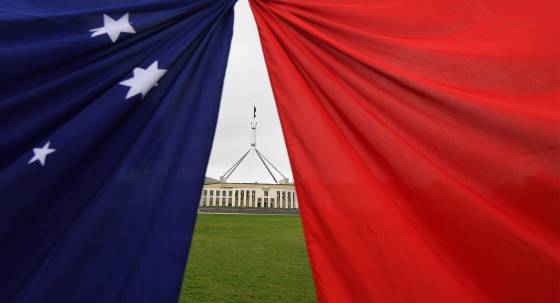 Parliament House seen behind an Australian and a Chinese flag, Canberra (Image: AAP/Lukas Coch)