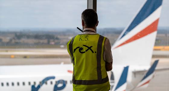 A Rex Airlines worker looks on as a plane arrives (Image: AAP/Luis Ascui)