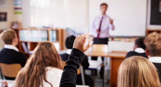 Female Student Raising Hand To Ask Question In Classroom